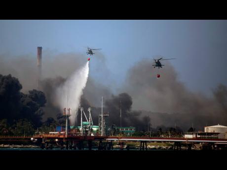 Helicopters hauling water fly over the Matanzas Supertanker Base, on Monday, August 8, 2022, as firefighters and specialists work to quell the blaze which began during a thunderstorm in Matanzas, Cuba.