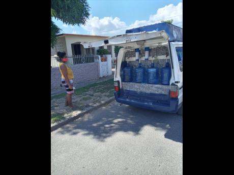 A customer has her bottles refilled with purefied water from a Puri-Fresh delivery van.