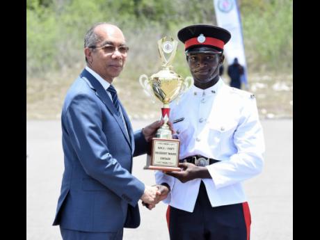 National Security Minister Dr Horace Chang (left) presents Constable A.J. Wilson with a trophy for attaining the highest mark among the 120 recruits of Batch 136 during their passing out parade at the National Police College of Jamaica in St Catherine on T