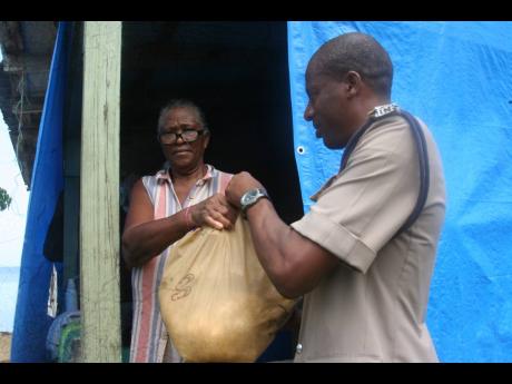 A presentation of goods being made to Merlene Thompson by Inspector of Police Mervin Hodges.