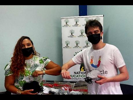  Shirley Moncrieffe, acting director, donor partnerships and management, National Education Trust (left) receiving a handover of masks from Rhys Greenland ,co-founder, Unicycle Jamaica. 