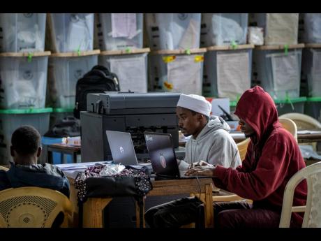 Electoral workers sit next to stacked ballot boxes after tallying finished in the Shauri Moyo area of Nairobi, Kenya Friday, August 12, 2022. Kenyans are waiting for the results of a close presidential election in which the turnout was lower than usual. 