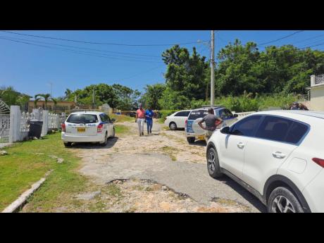 Detectives outside the Montego Hills, St James home of retired police Inspector Ralph Medley, who is suspected to have committed suicide some time on Thursday night into Friday morning.