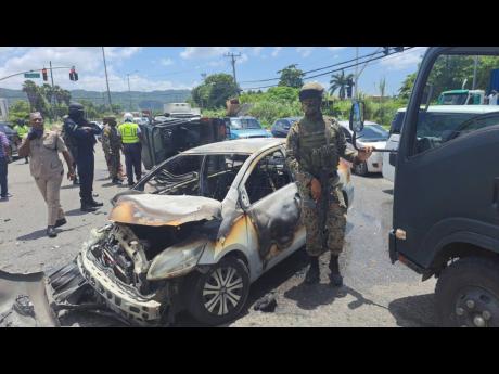 Members of the Jamaica Defence Force (JDF), the St James Police’s Traffic Department and the Jamaica Fire Brigade at the scene of a three-vehicle smash-up in Westgreen, Montego Bay, St James, on Friday. Two soldiers and a male civilian motorist were inju