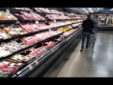 In this May 10, 2020, photo, a shopper pushes his cart past a display of packaged meat in a grocery store in southeast Denver.