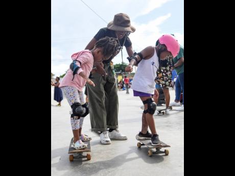 Kayla Wheeler helps Kharliegh Gayle (right) and Marley Bromley maintain their balance during a skateboarding session in Bull Bay, St Andrew, on Saturday. 