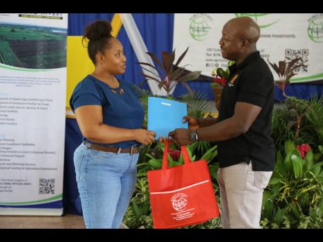 Pearnel Charles Jr, minister of agriculture and fisheries, hands over a lease agreement to Sharlene Anderson during a ceremony at Ebony Park HEART Academy in Clarendon on August 9.