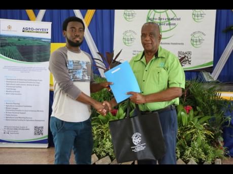 Franklyn Witter, state minister for agriculture, hands over a lease agreement to Dalkeith McDonald during a ceremony at Ebony Park HEART Academy Clarendon on August 9.