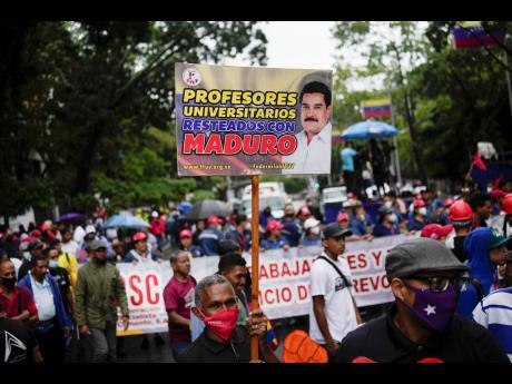 A teacher holds a sign that reads in Spanish, ‘University professors stand firm with Maduro’, referring to President Nicolas Maduro, during a pro-government protest by public workers demanding the government pay their full benefits and respect collecti