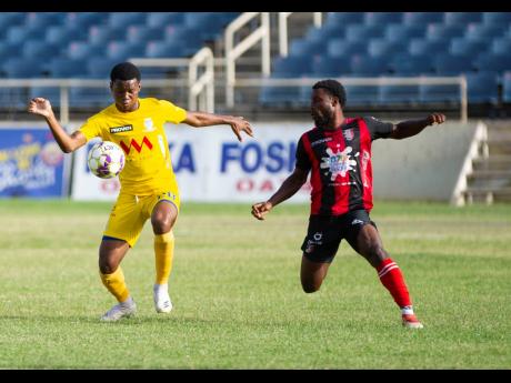 Harbour View’s Shawn Daley (left)  keeps his eyes on the ball while he is watched closely by Arnett  Gardens’ Ajuma Johnson during a Jamaica Premier League encounter  at Sabina Park last season.