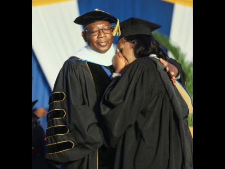 Waid-Ann Wedderburn, whose mom died from breast cancer months ago, is consoled as she accepts her degree from Dr Lincolnn Edwards, Northern Caribbean University president, at her graduation on Sunday.