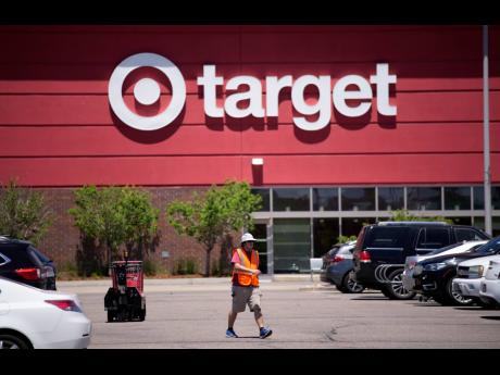 A worker collects shopping carts in the parking lot of a Target store on Wednesday, June 9, 2021, in Highlands Ranch, Colorado.