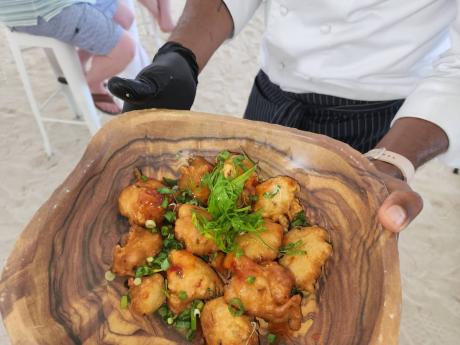 Chef Brian Lumley shows his finished product of salt fish fritters during a cooking class at AMRJamFest 3 at Secrets Resorts recently.