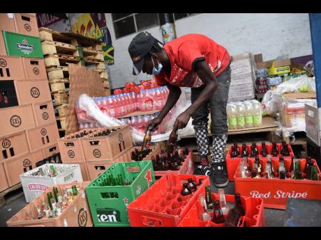Joel Reid, a worker at Papine Wholesale and Liquor Store Limited, sorts empty bottles that will be returned to Red Stripe. Retail and wholesale customers have been mandated to return empty bottles in order to make new purchases because of a bottle supply c
