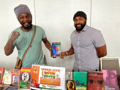Ras I-Nation (left) and Jahsun hold a copy of Ras I-Nation’s book titled ‘Start Fire’ at the Jamaica Poetry Festival at AC Hotel in Kingston on Sunday. 
