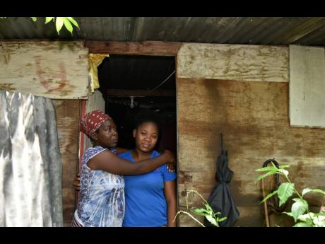 Fifty-three-year-old Dezreen Miller embraces her 23-year-old daughter, Anita Stephenson, in front of their home in Olympic Gardens, St Andrew. After living in the partially collapsed one-room structure for years, they are hopeful that better days are on th
