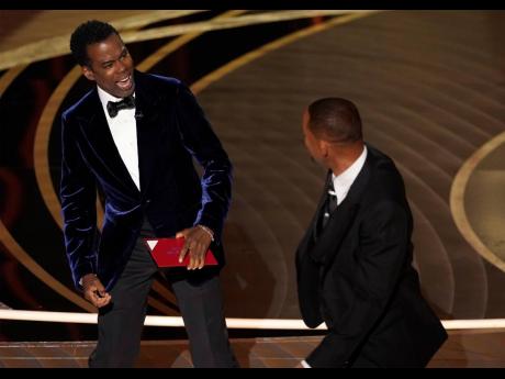 Presenter Chris Rock (left), reacts after being hit on stage by Will Smith while presenting the award for Best Documentary Feature at the Oscars.