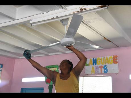 Cavell Martin cleans a ceiling fan in a classroom at Friendship Primary School in Spanish Town, St Catherine, ahead of the new academic year. 