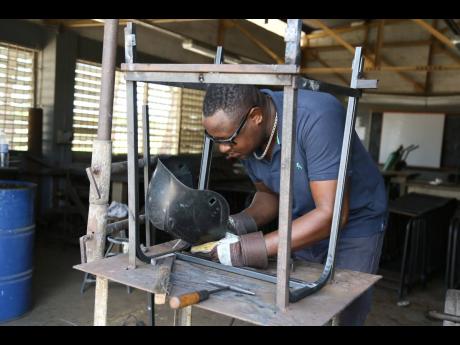 Burchell Simmonds, head of the Engineering Department at Vere Technical High School in Clarendon, welds a desk that’s a part of the Ministry of Education’s  furniture for schools project.