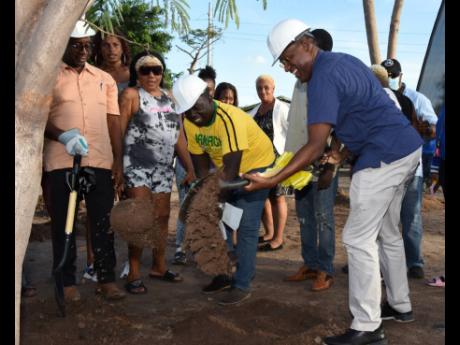 Andrew Swaby (left), councillor for the Vineyard Town division, looks on as Dr Nigel Clarke (right), minister of finance and member of parliament for St Andrew North Western, and Andrew Harris, councillor of the Hughenden division, turn their shovels durin