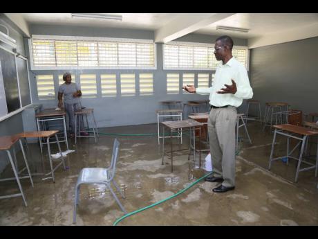 Acting Principal O’Neil Lewin visits as classroom at Vere Technical High while a worker carries undertakes cleaning duties as the Clarendon-based school prepares for the new academic year.