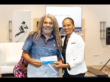 Joseph Heron, chairman of The Affirming Fathers Project cheerfully collects his prize for participating in the Johnnie Walker sponsored Men-Tell Workshop from Ruthlyn Johnson, JPS Customer Service Area Manager - East. 