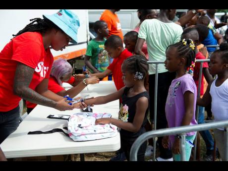 Popcaan Care Foundation staff distribute school bags during the Popcaan Off-To-School Fun Day.