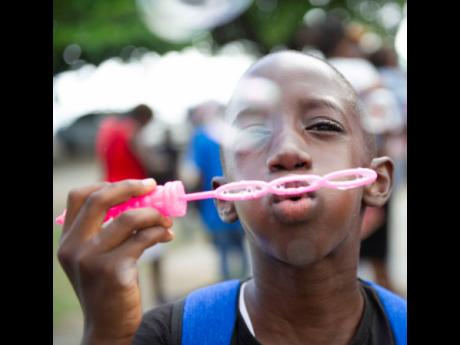 Nathanel Thompson blows bubbles during the Popcaan Off-To-School Fun Day, where approximately 1,000 children were fêted by dancehall deejay and St Thomas native, Popcaan. 
