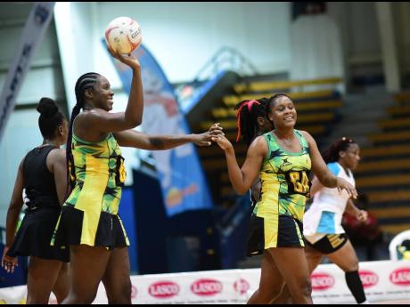 Sunshine Girls captain Jhaniele Fowler (with ball) celebrates with teammate Amanda Pinkney (right) during last year’s Sunshine Series netball match against Trinidad and Tobago at the National Indoor Sports Centre in Kingston.
