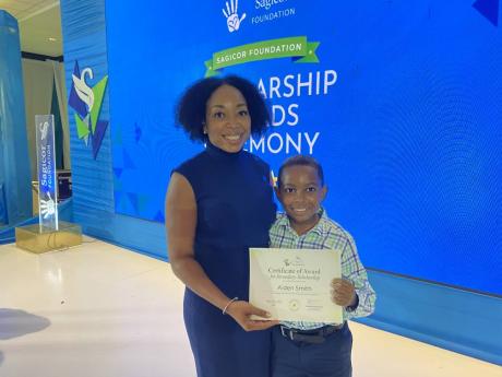 Aiden Smith holds his certificate with his mother, Renee Smith, at the Sagicor Foundation Scholarship and Awards Ceremony on Monday.