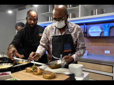 Chef Oji Jaja, the executive culinary artist at the Jamaica Food and Drink Kitchen, helps Edmund Bartlett, minister of tourism, to prepare parmesan polenta pan-seared salmon at the event’s launch in Barbican on November 18, 2021.