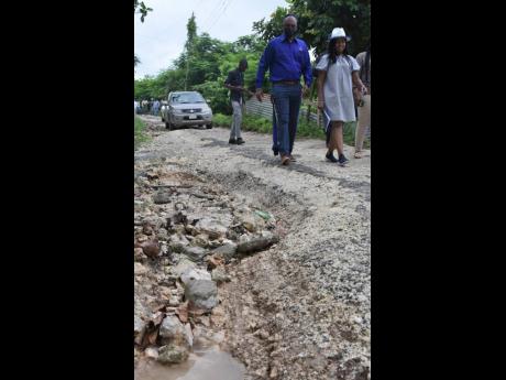 Omar Sweeney, managing director of the Jamaica Social Investment Fund), and St Thomas Eastern Member of Parliament Dr Michelle Charles walk along a section of the Hill 60 roadway in Cheswick, St Thomas, on Tuesday as and other officials toured the area, wh