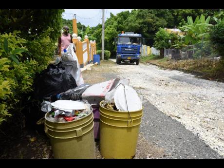A resident of Cheswick, St Thomas, carries out garbage as a collection truck visited the community on Tuesday, an hour before a tour led by Local Government and Rural Development Minister Desmond McKenzie. Residents said that it was the first time a garbag