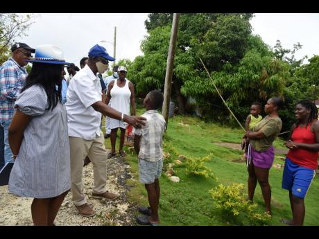 Local Government and Rural Development Minister Desmond McKenzie (third left) engages six-year-old Delano Wright in conversation as he greeted residents of Cheswick, St Thomas, during a tour on Tuesday. Looking on (from left) are Dalvey Division Councillor