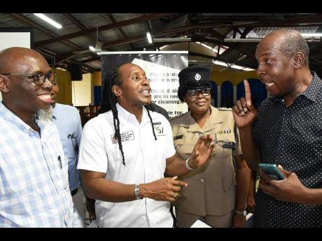 Jephet Williams (right), president of the Happy Content Benevolent Society, engages in an animated discussion with St Catherine East Central Member of Parliament Alando Terrelonge (centre) at a stakeholder meeting on the widening of Grange Lane in Portmore
