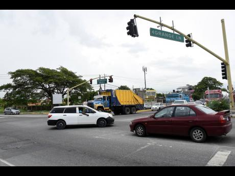 Motorists drive through the intersection of Grange Lane and Municipal Boulevard in Portmore on Thursday. Grange Lane will be expanded from two lanes to four. Work is scheduled to start in October.