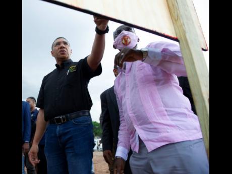 Prime Minister Andrew Holness (left) and Kingston Western Member of Parliament Desmond McKenzie look at an architectural rendition of the Victoria Palms housing development for which ground was broken on Friday in Denham Town.