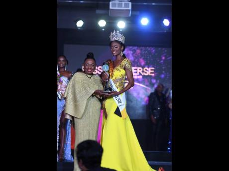Minister of Culture, Gender, Entertainment and Sport Olivia Grange (left) present the Miss Universe Jamaica 2022 title winner trophy to new titleholder, Toshami Calvin. 