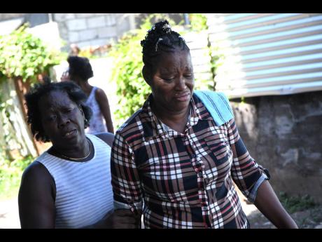 Marcia Powell (left) consoles Doreen Jackson-Smikle, widow of Lennox Smikle and mother of Tafina Thomas, who were gunned down in Eight Miles, Bull Bay, Friday night. 