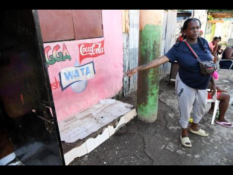 Keneisha Murray, aunt of Nevado Maitland, slain student of Tivoli Gardens High, points the hole in the gate pierced by the bullet that killed the teenager. He was killed inside the family home on Fourth Street in Trench Town, Kingston, Friday. 