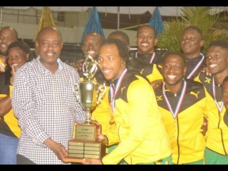 Jamaica’s male netball captain Kurt Dale (right) collects the winning trophy from Fredrick Stephenson, Minister of Public Service, Consumer Affairs and Sports of St Vincent and Grenadines, after the Jamaican team topped the  Americas Netball Championship