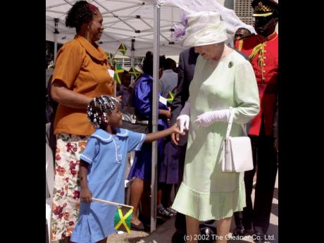 A schoolgirl touches the hand of Queen Elizabeth II on her 2002 visit to Jamaica.