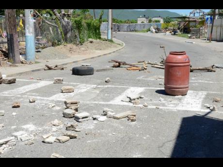 Debris scattered across a section of the road in the Top Jungle area of Arnett Gardens, St Andrew, on Friday as residents block the path of vehicles out of fear that another drive-by shooting could occur in the community.