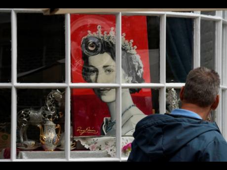 A man looks at a portrait of Queen Elizabeth II in a shop window near Windsor Castle in Windsor, England, Friday, September 9, 2022. Queen Elizabeth II, Britain’s longest-reigning monarch and a rock of stability across much of a turbulent century, died T