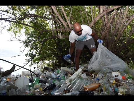 Shawn Watson of BTR Customs picks up plastic bottles along the Gun Boat Beach in Kingston on Saturday. He was among more than 200 volunteers organised by the GraceKennedy Foundation who turned out along the Palisadoes Strip for the clean-up drive ahead of 