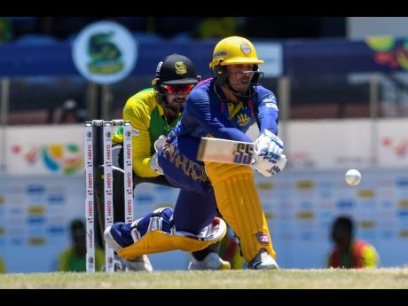 Quinton de Kock (right) of Barbados Royals hits a boundary while  Amir Jangoo of Jamaica Tallawahs looks on during the 2022 Hero Caribbean Premier League match between Jamaica Tallawahs and Barbados Royals at the Daren Sammy National Cricket Stadium in Gro