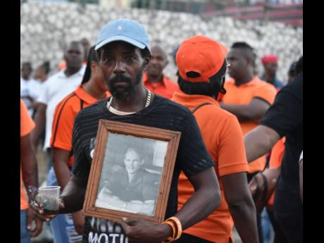 A People’s National Party supporter holds a photograph of former party President Michael Manley at Sunday’s St Andrew Southern constituency conference in Arnett Gardens. 