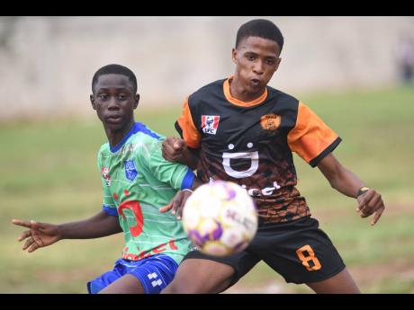 Tivoli High School’s  Odean Wilson (right)  controls the ball ahead of  Vauxhall High’s Dontez Miller  during yesterday’s Manning Cup encounter at the Tivoli High School field. Tivoli won 4-0.