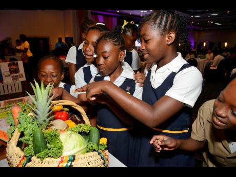 Enthusiastic students from Port Morant Primary School in St Thomas are fascinated by this basket containing an attractive array of fruits and vegetables at the 4-H Club booth during the Ministry of Health and Wellness’s Caribbean Nutrition Day National S
