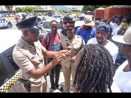 Deputy Superintendent Linval Phoenix of the Kingston Central Police Division interacts with Eastern St Andrew route taxi operators who led a protest in downtown Kingston demanding that their licence not be revoked because of multiple traffic violations.